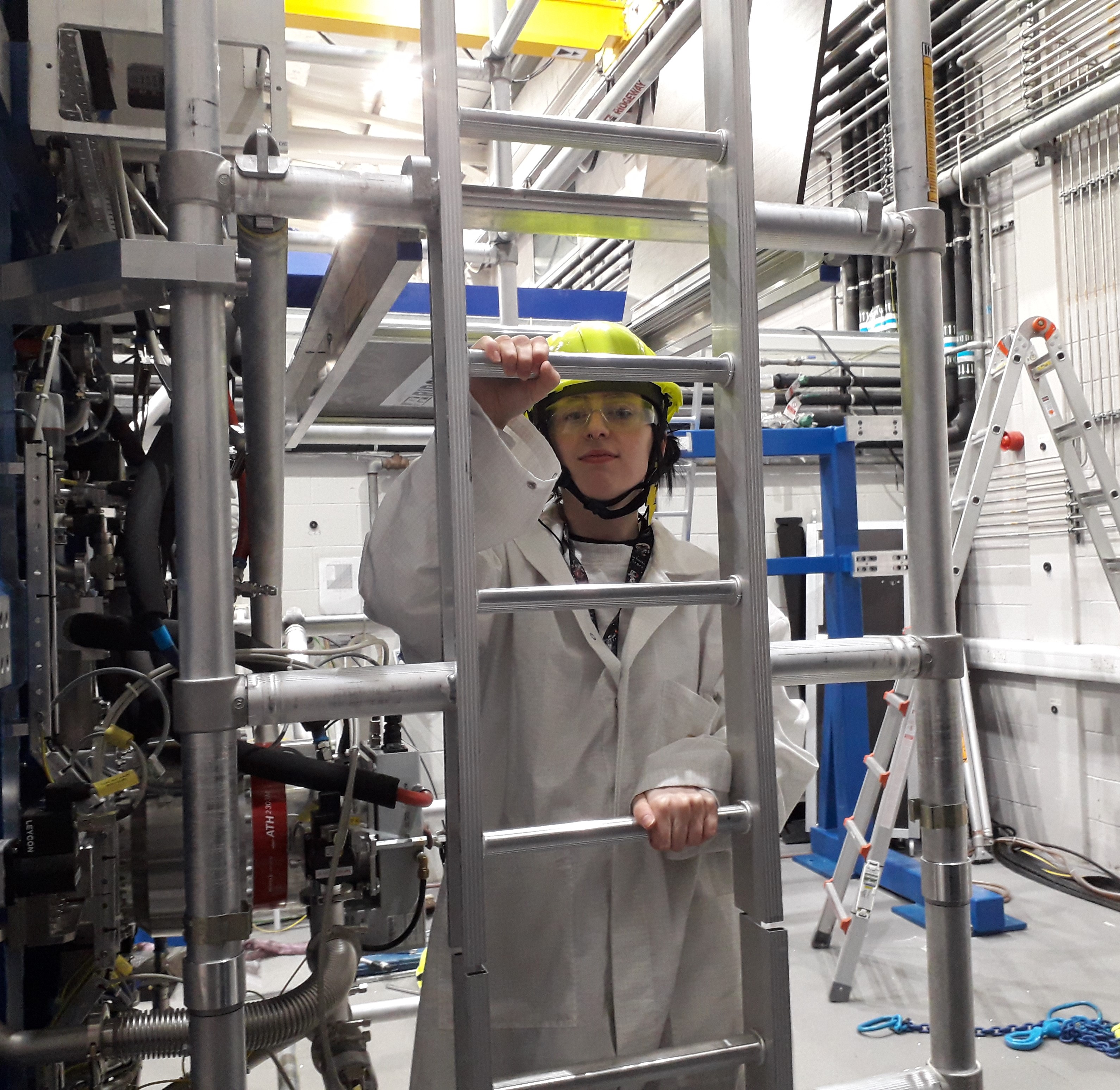 An apprentice in hard hat and lab coat working in the lab at UK ATC.